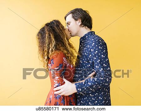 Couple kissing against yellow background View Large Photo Image Stock Image - Couple kissing against yellow background. Fotosearch