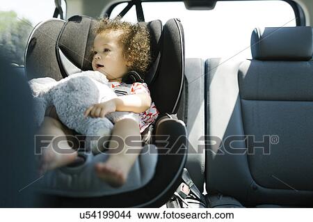 Girl (12-17) sitting on car seat and holding plush toy View Large Photo Image Picture - Girl (12-17) sitting on car seat and holding plush toy. Fotosearch
