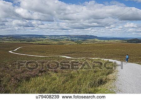 Stock Photo - Ireland, Cavan County, Cuilcagh Mountain Park, Woman walking along winding road. Fotosearch
