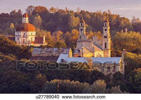 Stock Image - Lithuania, Vilnius, morning view of churches among trees. Fotosearch