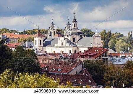 Stock Photo - Lithuania, Vilnius, Storm clouds above church and residential buildings. Fotosearch