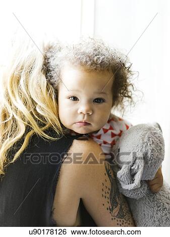 Stock Photograph - Mother embracing daughter (12-17 months). Fotosearch