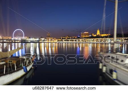 Stock Photo - Spain, Andalusia, Seville, Waterfront with sailboats in foreground. Fotosearch