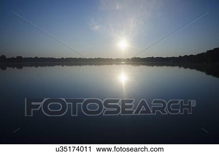 Sun rising above lake View Large Photo Image Stock Image - Sun rising above lake. Fotosearch