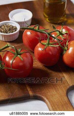 Stock Photography - Tomatoes, pepper, salt and olive oil on cutting board. Fotosearch