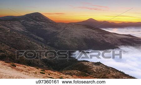 Stock Image - Ukraine, Zakarpattia region, Rakhiv district, Carpathians, Chornohora, Sheshul, Mist over mountains at dawn. Fotosearch