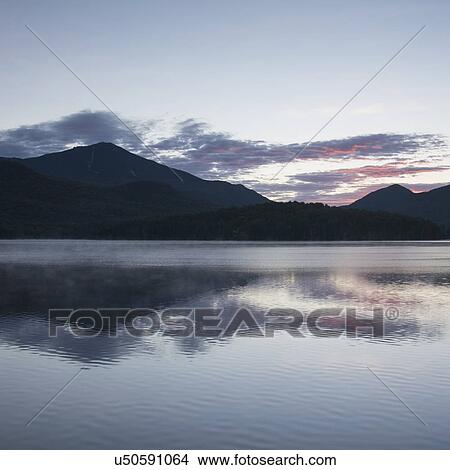 Picture - USA, New York, Lake Placid, Mountain and clouds reflecting in lake. Fotosearch