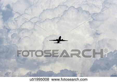 Stock Photo - Airplane in sky with clouds in background. Fotosearch