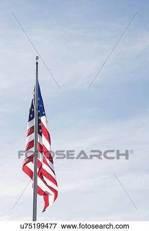 Stock Photo - American flag against blue sky. Fotosearch