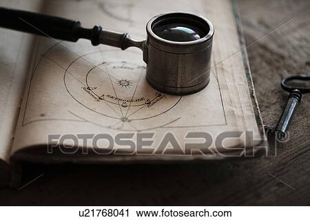 Stock Image - Antique magnifying glass and book. Fotosearch