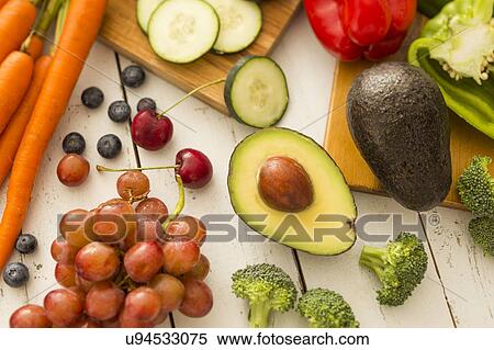 Stock Photography - Avocado and red grapes surrounded by fruits and vegetables. Fotosearch
