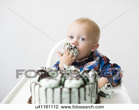 Stock Image - Baby boy (12-17 months) eating birthday cake. Fotosearch