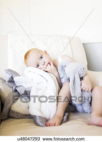 Stock Image - Baby boy (12-17 months) holding stuffed rabbit. Fotosearch