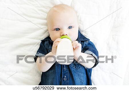 Baby boy (12-17 months) lying on back and drinking milk in bottle View Large Photo Image Stock Photo - Baby boy (12-17 months) lying on back and drinking milk in bottle. Fotosearch