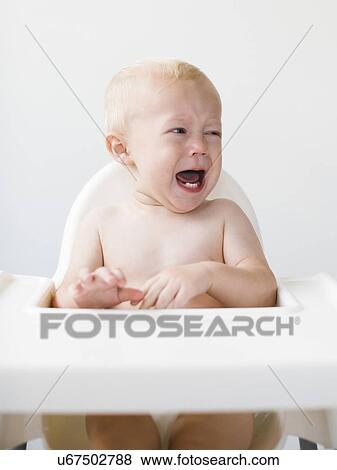 Baby boy (12-17 months) sitting in high chair and crying View Large Photo Image Stock Photo - Baby boy (12-17 months) sitting in high chair and crying. Fotosearch
