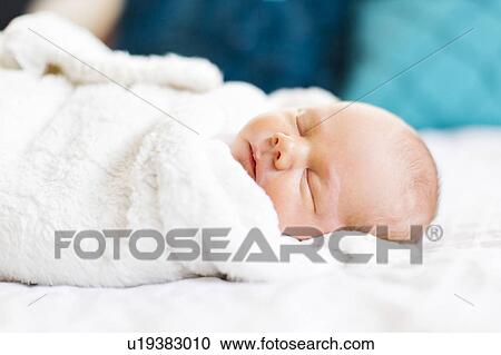 Stock Image - Baby boy (2-5 months) sleeping in white blanket. Fotosearch