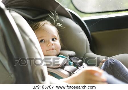 Baby girl (12-17 months) sitting in baby car seat during car trip View Large Photo Image Stock Photo - Baby girl (12-17 months) sitting in baby car seat during car trip. Fotosearch