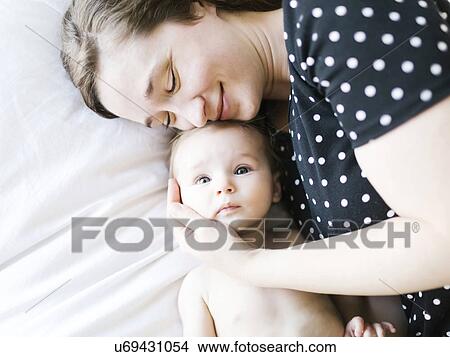 Picture - Baby girl (6-11 Months) being hugged by mother, directly above. Fotosearch