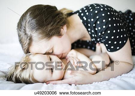 Stock Photograph - Baby girl (6-11 Months) being hugged by mother. Fotosearch