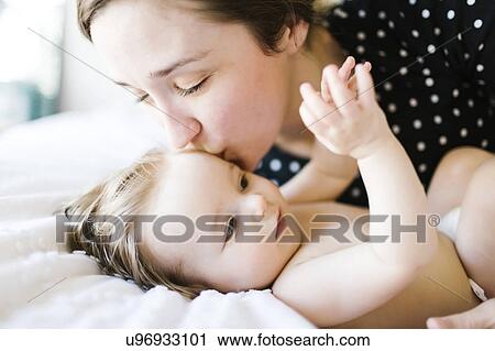 Baby girl (6-11 Months) being kissed by mother View Large Photo Image Stock Image - Baby girl (6-11 Months) being kissed by mother. Fotosearch