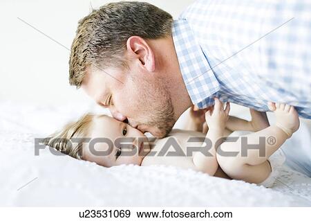 Baby girl (6-11 Months) being kissed by father View Large Photo Image Stock Photo - Baby girl (6-11 Months) being kissed by father. Fotosearch