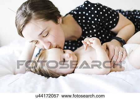 Baby girl (6-11 Months) being kissed by mother View Large Photo Image Stock Photo - Baby girl (6-11 Months) being kissed by mother. Fotosearch