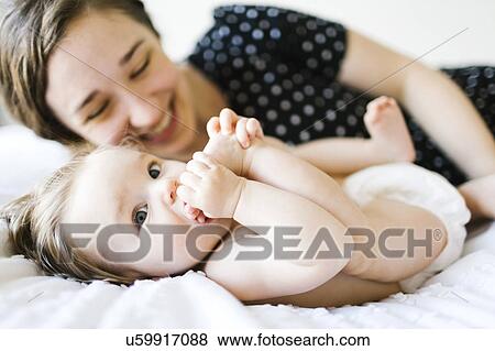 Stock Photo - Baby girl (6-11 Months) biting foot. Fotosearch