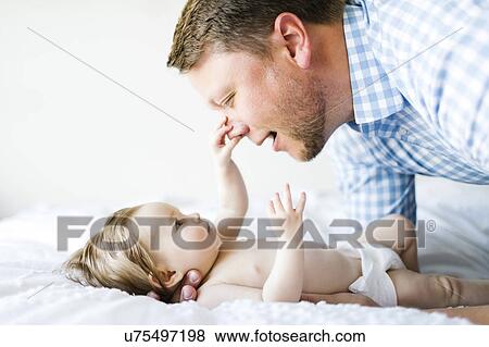 Stock Photo - Baby girl (6-11 Months) catching father`s nose. Fotosearch