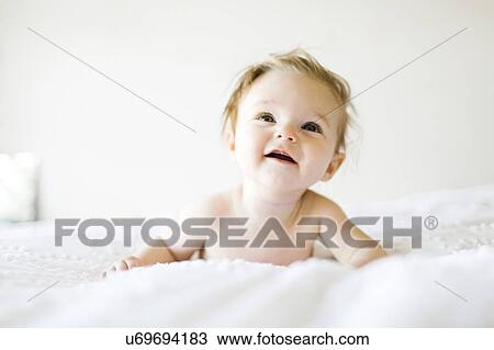 Stock Image - Baby girl (6-11 months) playing in bedroom. Fotosearch