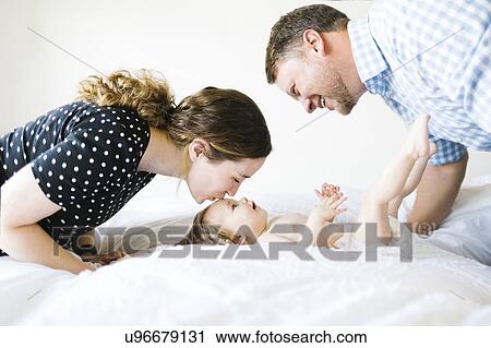 Stock Image - Baby girl (6-11 Months) spending time with parents. Fotosearch