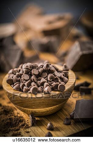 Stock Image - Bowl of chocolate chips on cutting board. Fotosearch
