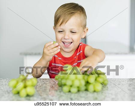 Stock Photo - Boy (2-3) eating white grapes. Fotosearch