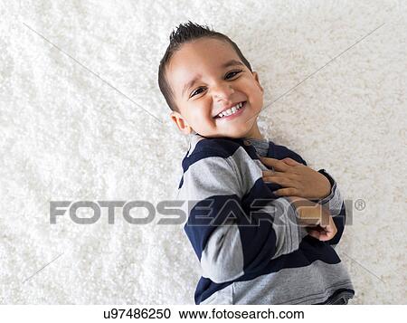 Stock Image - Boy (2-3) lying down on carpet and laughing. Fotosearch