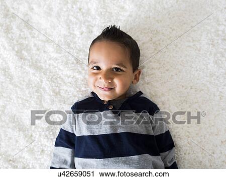 Boy (2-3) lying down on carpet View Large Photo Image Stock Image - Boy (2-3) lying down on carpet. Fotosearch
