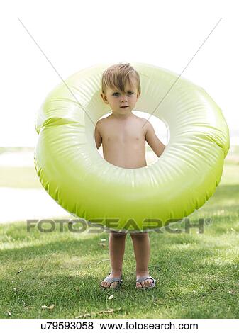 Stock Photo - Boy (2-3) standing with inflatable ring. Fotosearch