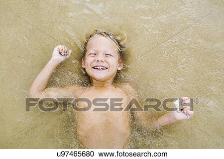 Stock Image - Boy (4-5) playing at beach. Fotosearch