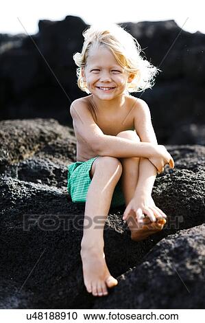 Stock Image - Boy (4-5) playing on rocks. Fotosearch