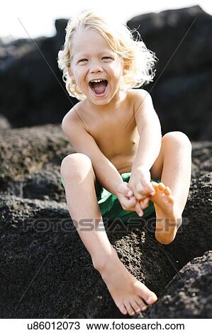 Stock Image - Boy (4-5) playing on rocks. Fotosearch