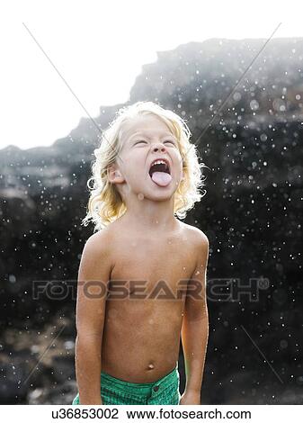 Stock Image - Boy (4-5) playing with rain. Fotosearch