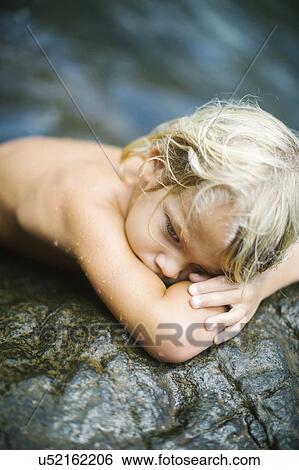 Boy (4-5) resting on rocks View Large Photo Image Stock Photograph - Boy (4-5) resting on rocks. Fotosearch