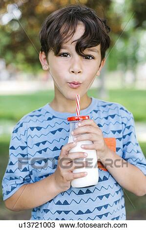 Boy (6-7) drinking milk with straw in park View Large Photo Image Stock Image - Boy (6-7) drinking milk with straw in park. Fotosearch