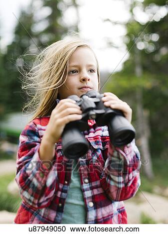 Stock Image - Boy (6-7) using binoculars. Fotosearch