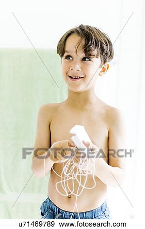 Stock Photo - Boy (6-7) with dental floss. Fotosearch