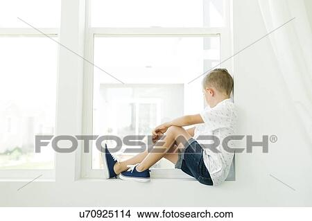 Picture - Boy (7-8) looking through window. Fotosearch