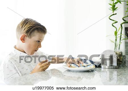 Boy (8-9) eating cookies View Large Photo Image Stock Photography - Boy (8-9) eating cookies. Fotosearch