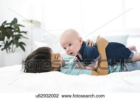 Boy ( 8-9 ) lying on bed and embracing brother ( 2-5 months ) View Large Photo Image Stock Image - Boy ( 8-9 ) lying on bed and embracing brother ( 2-5 months ). Fotosearch