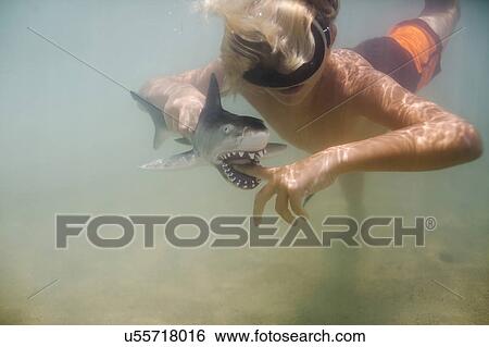 Boy (8-9) playing with toy shark in sea View Large Photo Image Stock Photograph - Boy (8-9) playing with toy shark in sea. Fotosearch