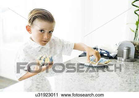 Boy (8-9) stealing cookies View Large Photo Image Stock Image - Boy (8-9) stealing cookies. Fotosearch