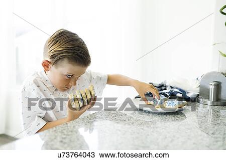 Stock Image - Boy (8-9) stealing cookies. Fotosearch