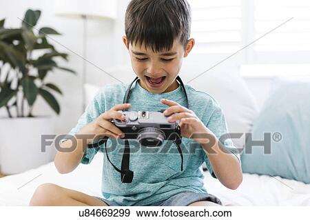 Boy (8-9) watching camera with curiosity View Large Photo Image Stock Photo - Boy (8-9) watching camera with curiosity. Fotosearch